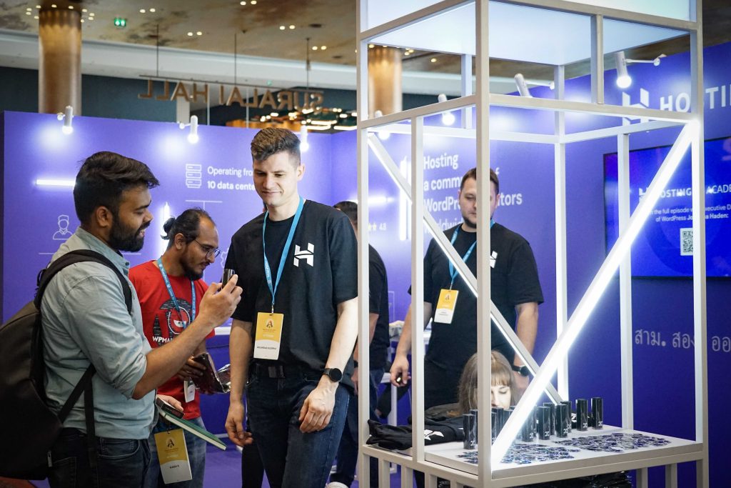 A Hostinger team member showing our merchandise to a booth visitor