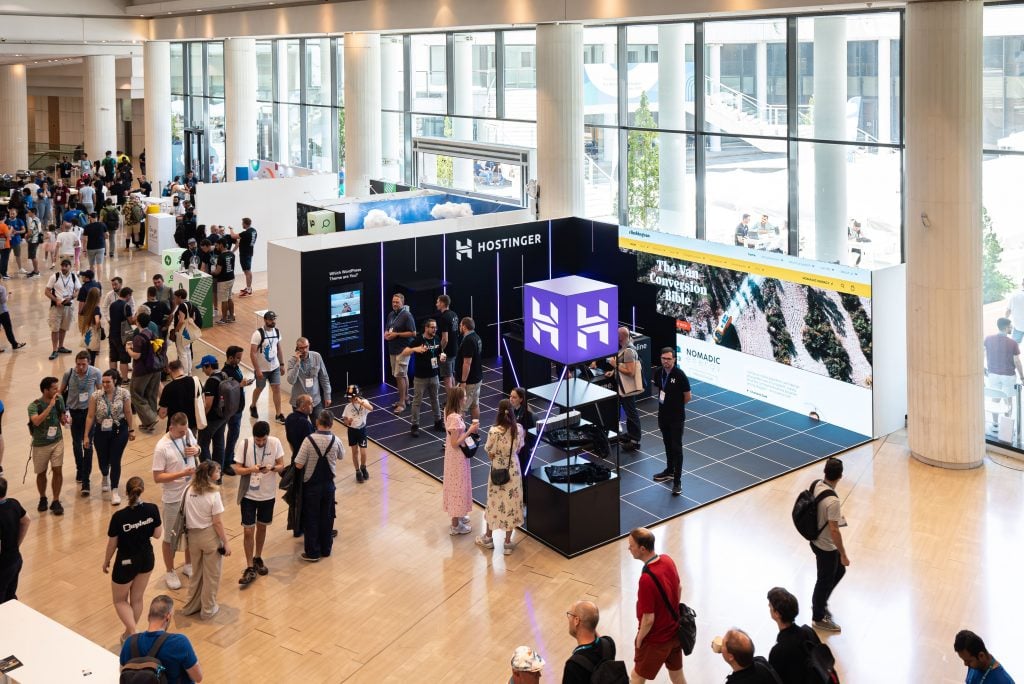 Hostinger's booth at WordCamp Europe 2023 that displayed our Client Stories videos in our huge video background